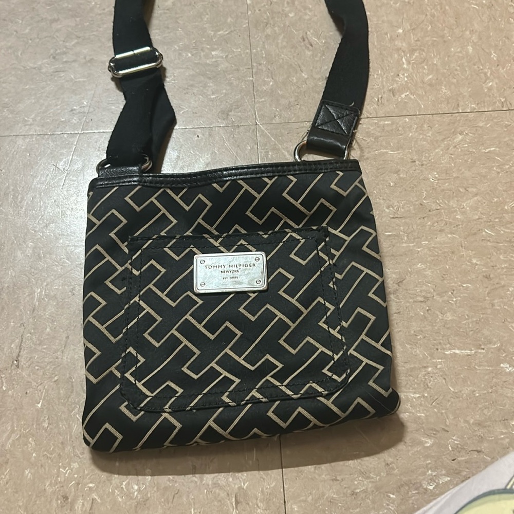A Tommy Hilfiger purse with adjustable straps and tan patterns on the outside